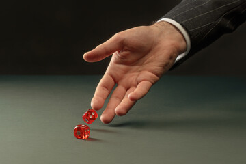 Man's hand throws red dice. Male hand rolls red dices on table. Concept of Casino game and luck....