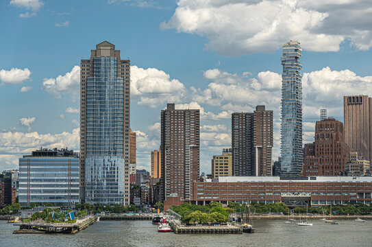 New York, NY, USA - August 1, 2023: City Headquarters building and 56 Leonard street skyscraper seen from Hudson river under blue cloudscape. Looking straight into N. Moore Street. Green tree line, pi