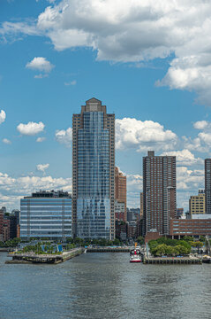 New York, NY, USA - August 1, 2023: City Headquarters building with glass front facade between green pier 25 and 26. Looking from Hudson river straight into N. Moore Street. blue cloudscape