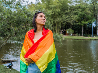 mujer hispano latina en el parque con la bandera del orgullo gay casual 