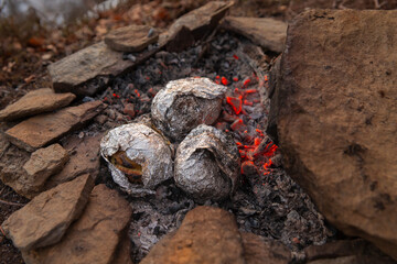Food cooked over a fire with a smoky aroma in cooking foil. Large roasting potatoes
