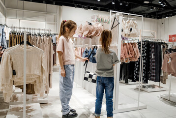 Two Young Girls Looking at Clothing in a Store