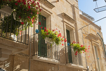 Old buildings with balconies with flower pots in Polignano a Mare, in Puglia, Italy.
