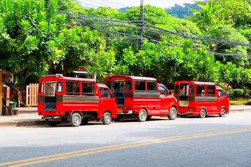 Three thai traditional red tuk tuk taxi (songthaew) in Krabi, Thailand.