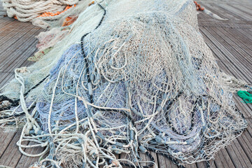 There is a large pile of fishing nets lying on the wooden pier to dry.