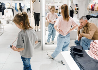 Father Watching His Daughters Try on Clothes in a Busy Clothing Store on a Winter Afternoon