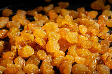 yellow raisins macro on black wood background