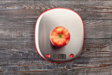apple on kitchen scales on wood background top view