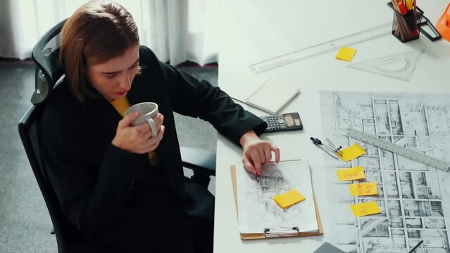 Top view of architect engineer drink coffee and draw blueprint at meeting table with equipment and safety helmet scatter around. Aerial view of project manager looking at project plan. Alimentation.