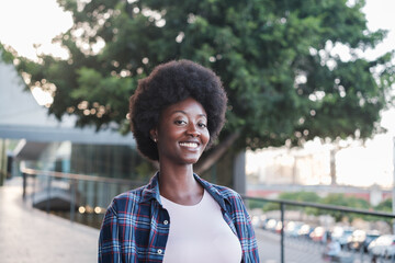 Portrait of student with afro hair smiling and walking around the faculty after leaving university