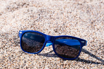 Sunglasses with blue lenses on the beach. On beach on bright sunny day.