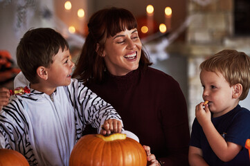 Fototapeta premium Happy family, mother and kids with pumpkin for halloween to celebrate with siblings, candy or smile. Home, mom or parent with children eating sweets in vegetable for holiday, decoration and party