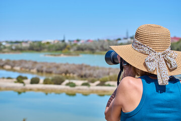 Fototapeta premium Tourist woman with summer hat taking photographs in the Santa Pola wetlands, Alicante, Valencian Community, Costa Blanca, Spain.