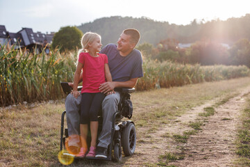 Moment of happiness, a little girl and her father a wheelchair user enjoying together time in...