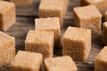 Cubes of refined cane sugar in closeup. Brown cane sugar cubes on wooden background.