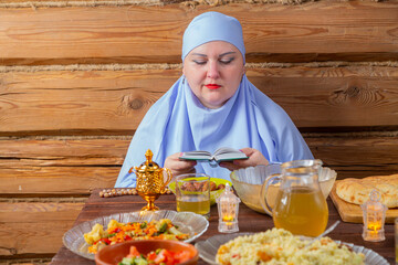 A Muslim woman in a blue hijab reads the Koran at the Iftar Ramadan table