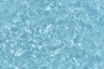 Blue water with ripples on the surface. Defocus blurred transparent blue colored clear calm water surface texture with splashes and bubbles. Water waves with shining pattern texture background.