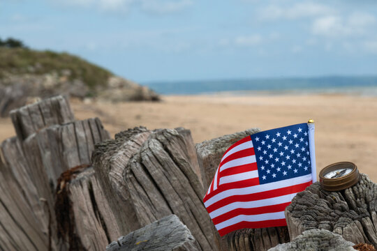Utah Beach WWII with Flag of USA in sharp focus with beach and ocean in background. Sandy beach and fence posts. Normandy France rememberance of Veterans Day. High quality photo