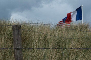 Normandy area of Utah beach. French, and USA flags are waving. Cloudy sky. High quality photo