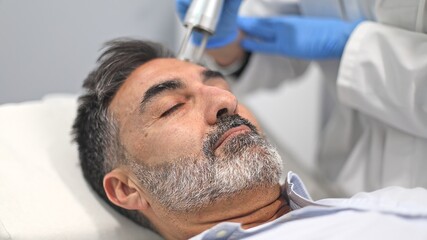 Doctor performing skin treatment on patient with advanced device.