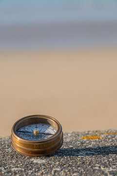 Compass on stone ledge overlooking ocean sand and sky in bakground. Background image. concept of finding direction in life. Verticle selective focus copyspace. High quality photo