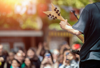 Back view of a male musician guitarist on stage with audience in a crowded concert. Heavy metal...