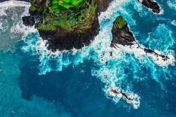 Aerial view of rough ocean with waves, volcanic beach and swiming pool in Seixal, Madeira, Portugal