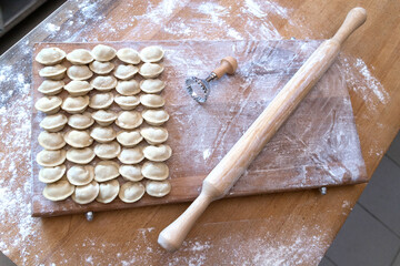 The raw dumplings were placed on a wooden cooking board. Next to it is a rolling pin for rolling...