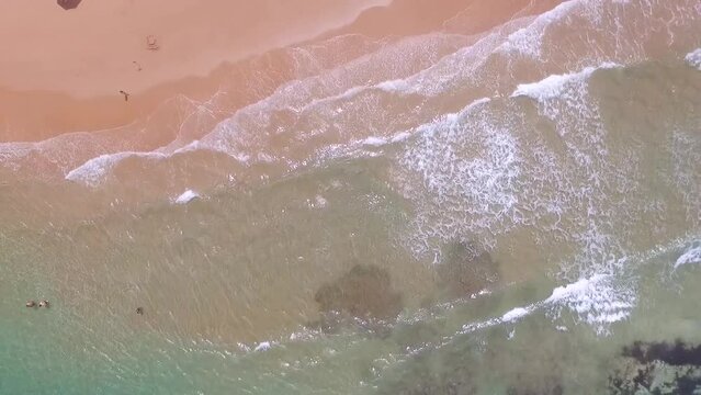 Drone parado filmando de cima ondas azuis quebrando na praia em mares do nordeste brasileiro, em Taipus de Fora, Bahia