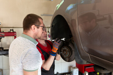 The repairman tells the client the reasons for the breakdown in the car. service center, car...