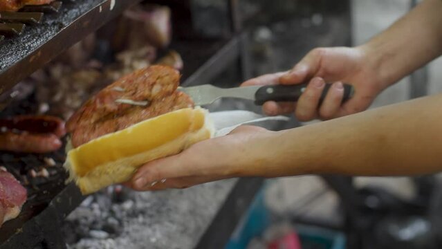 Parrillero, chef, arma un choripan con un chorizo y un pan en slowmotion. Parrilada, Asado, parrilla. 