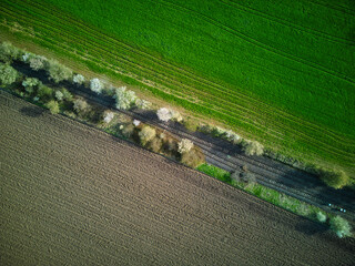 aerial view on an abandoned railroad track with a green and brown field surrounding