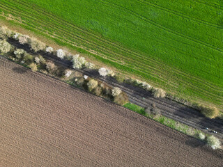 aerial view on an abandoned railroad track with a green and brown field surrounding