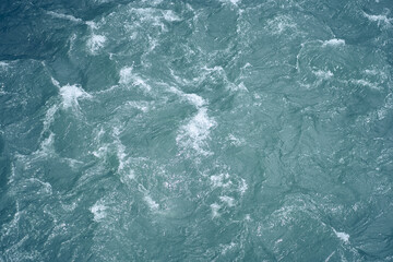 Ripples and waves on the water. Beautiful background with blue water and a place to copy. Close-up of raging water. High quality photo