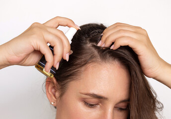 woman with spray bottle with oil, empty label, in hands,for hair care.girl with beautiful, natural...