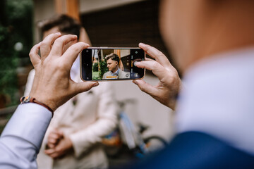 Riga, Latvia, - August 26, 2024 - Man taking a photo of another man with a smartphone, outdoors.