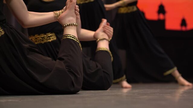 The legs of four young Indian dancers performing folk dances on stage. Women in traditional clothes dancing. High quality 4k footage