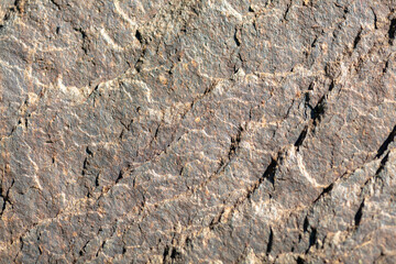 Close-up of Rough Stone Surface Texture with Natural Cracks and Patterns in Sunlight, Detailed Background for Geology, Construction, and Natural Material Concepts