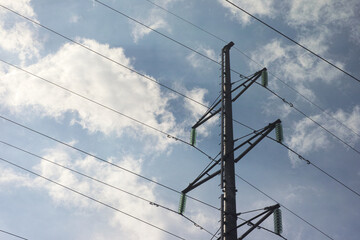 Power lines and a pylon on a cloudy sky background. Close up.