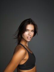 Fototapeta premium Young slim athletic brunette on a gray background. Active lifestyle, weight loss, motivation.