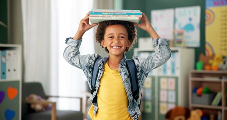 Child, face and book on head in school classroom for education learning in kindergarten,...