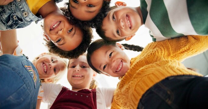 Huddle, support and happy children in school for education, community or development. Low angle, diversity and group of friends with smile in playground for solidarity, teamwork or playing together
