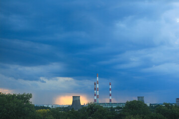 Pipes of thermoelectric power station against sunset and cloudy sky