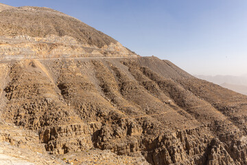 Jebel Jais mountain peak with winding tarmac road cutting the slope and zipline above, United Arab Emirates.