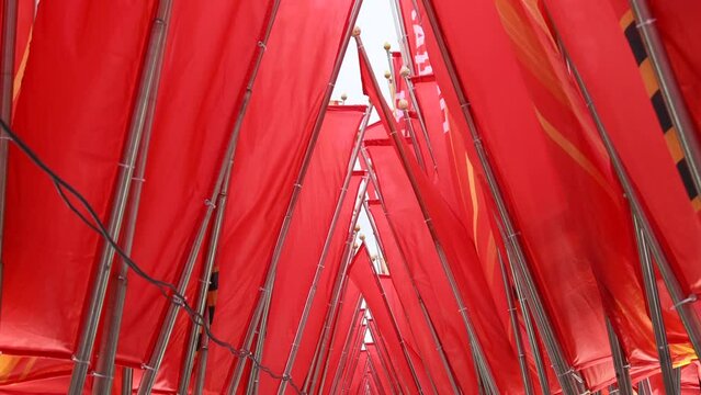 Close-up side view of group of red flags with russian word Victory swaying during Victory Day celebration in a cloudy spring day in Moscow, Russia. Soft focus. Russian holidays decorations theme.