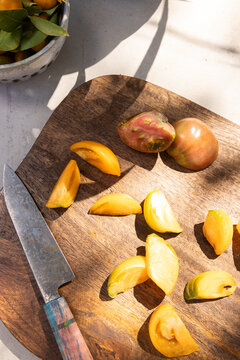 Still life in an outdoor kitchen with organic heirloom tomatoes on a wood cutting board. 