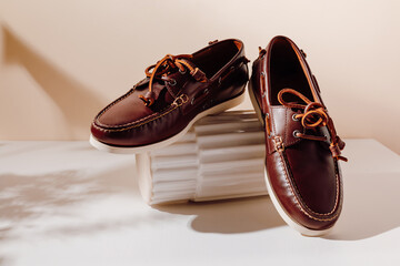 Men's brown leather moccasins shoes on the showcase with aesthetic shadows, fashion concept.