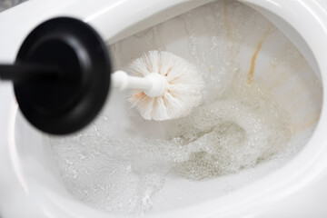 Сlose-up shot of a housewife in rubber gloves cleaning a toilet using a special cleaning product and a brush	