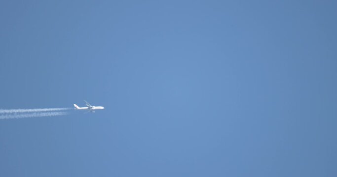 The flight of a white plane through the blue sky from left to right up. Immersion trace. Close-up. Slow motion.