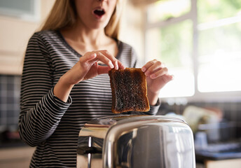 Woman, burnt and toast for breakfast in kitchen as cooking disaster, fail and accident as mistake...